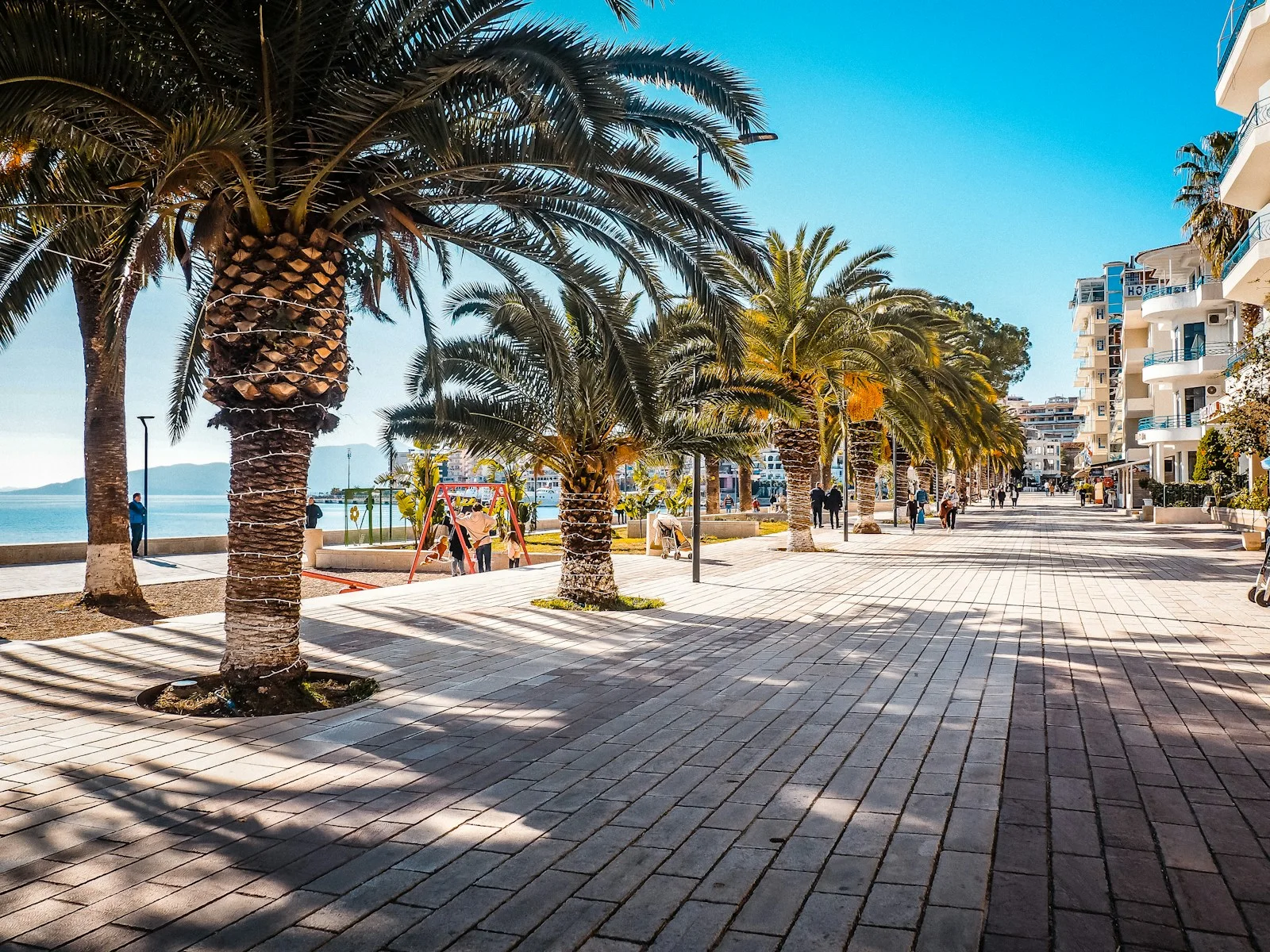 Slnečná promenáda s palmami pri mori v Sarande v Albánsku.